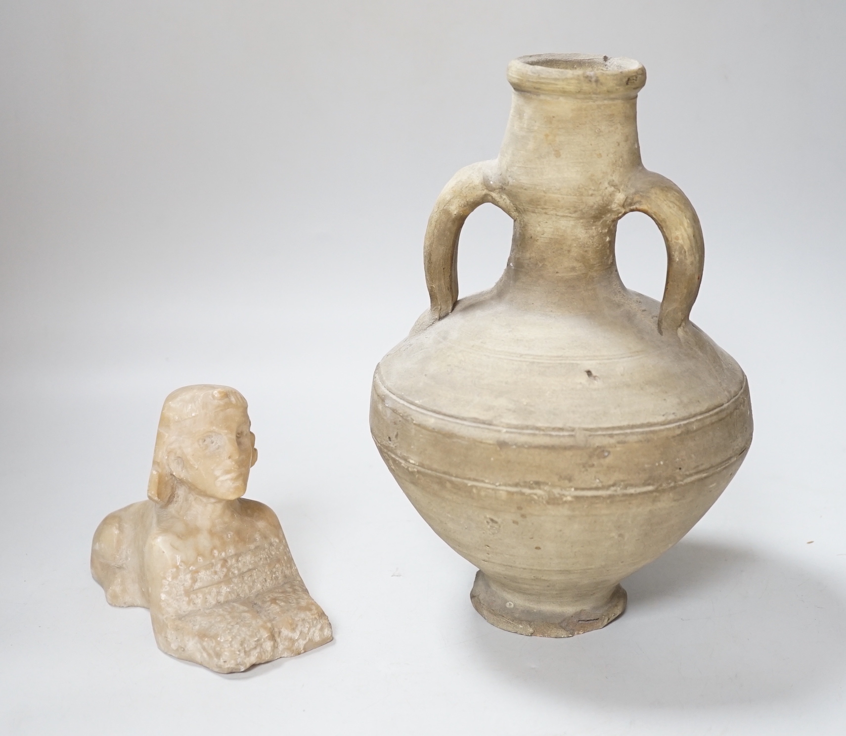 An Egyptian style alabaster model of a sphinx and a twin handled pottery vase, the largest 25cm high